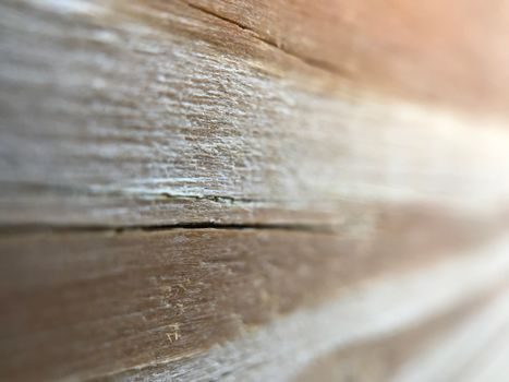 gros plan sur une lame de parquet en bois gondolée et soulevée en vagues, éclairage naturel latéral qui accentue le relief